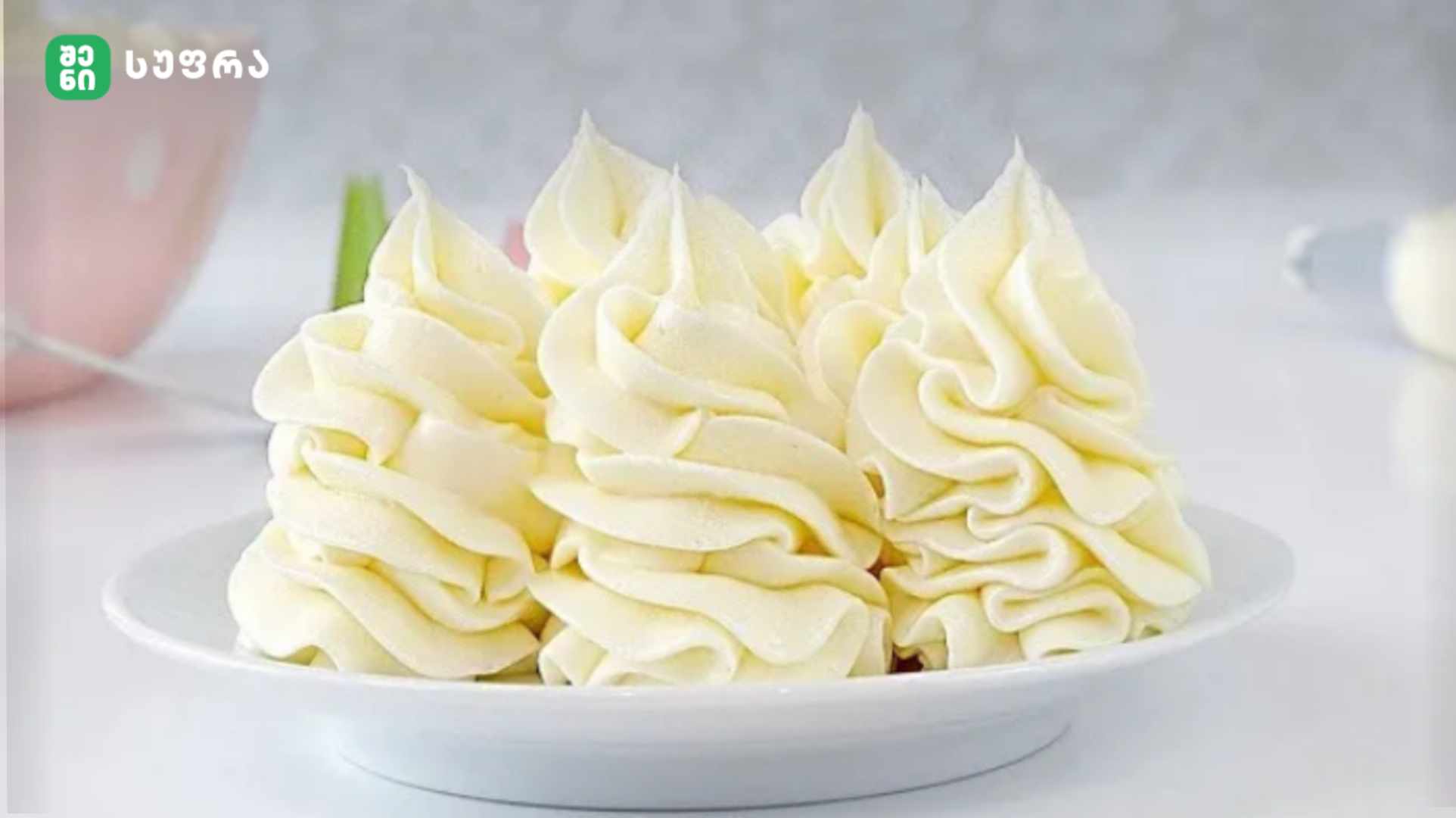White frosted cake piled with piped rosette buttercream decorations on a white plate.