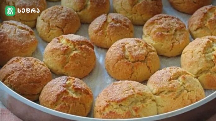 Tray of small, golden-brown sugar-dusted biscuits cooling on a metal baking tray