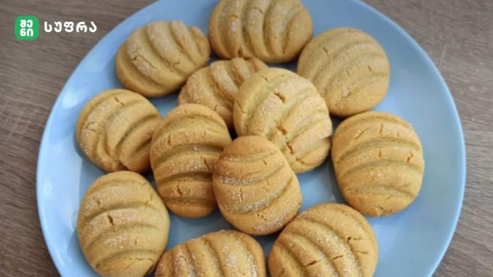 Blue plate piled with golden round cookies that have ridged scoring and a light dusting of sugar, ready to serve