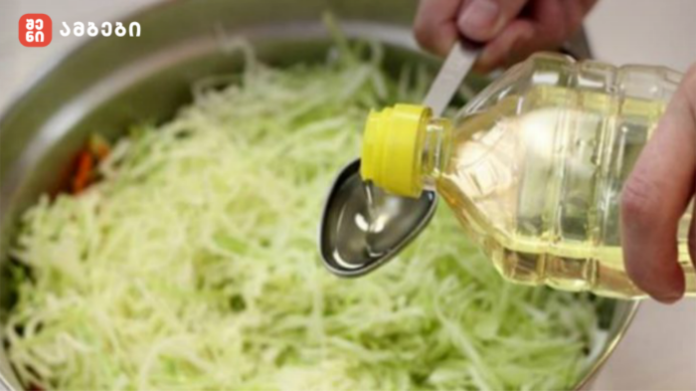 Person pouring cooking oil into a bowl of shredded cabbage for salad.