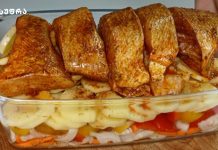თევზი გარნირით Roasted chicken pieces arranged over sliced potatoes and onions in a glass baking dish, seasoned with spices and ready to serve.