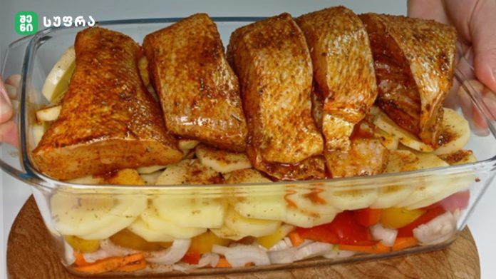 Roasted chicken pieces arranged over sliced potatoes and onions in a glass baking dish, seasoned with spices and ready to serve.