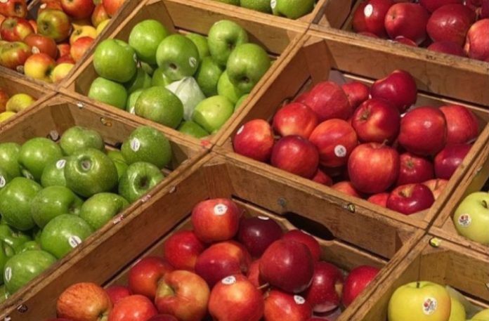 vashli Crate display of green and red apples in wooden boxes at a market stall.
