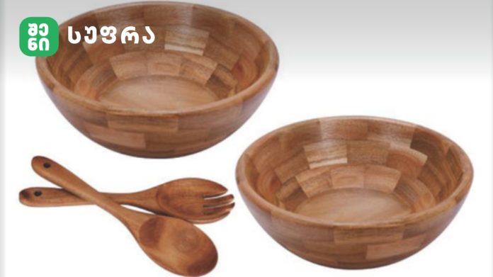Set of three wooden bowls with matching wooden utensils (spoons and fork) on a white background.
