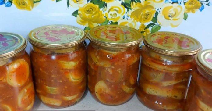 Five glass jars of homemade pickled vegetables in orange-red sauce, lined up on a shelf against a bright floral backdrop of yellow flowers.