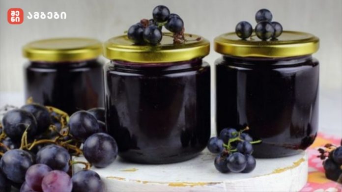 Three jars of blueberry jam with gold lids on a white surface, blueberries scattered around.