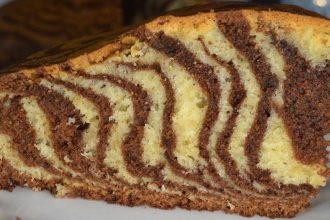 Slice of zebra cake with alternating vanilla and chocolate swirls on a white plate