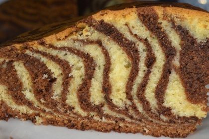 Slice of zebra cake with alternating vanilla and chocolate swirls on a white plate