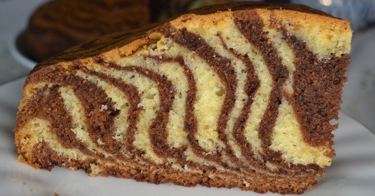 Slice of zebra cake with alternating vanilla and chocolate swirls on a white plate
