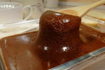 Chocolate lava cake being lifted with a wooden spatula from a glass baking dish.