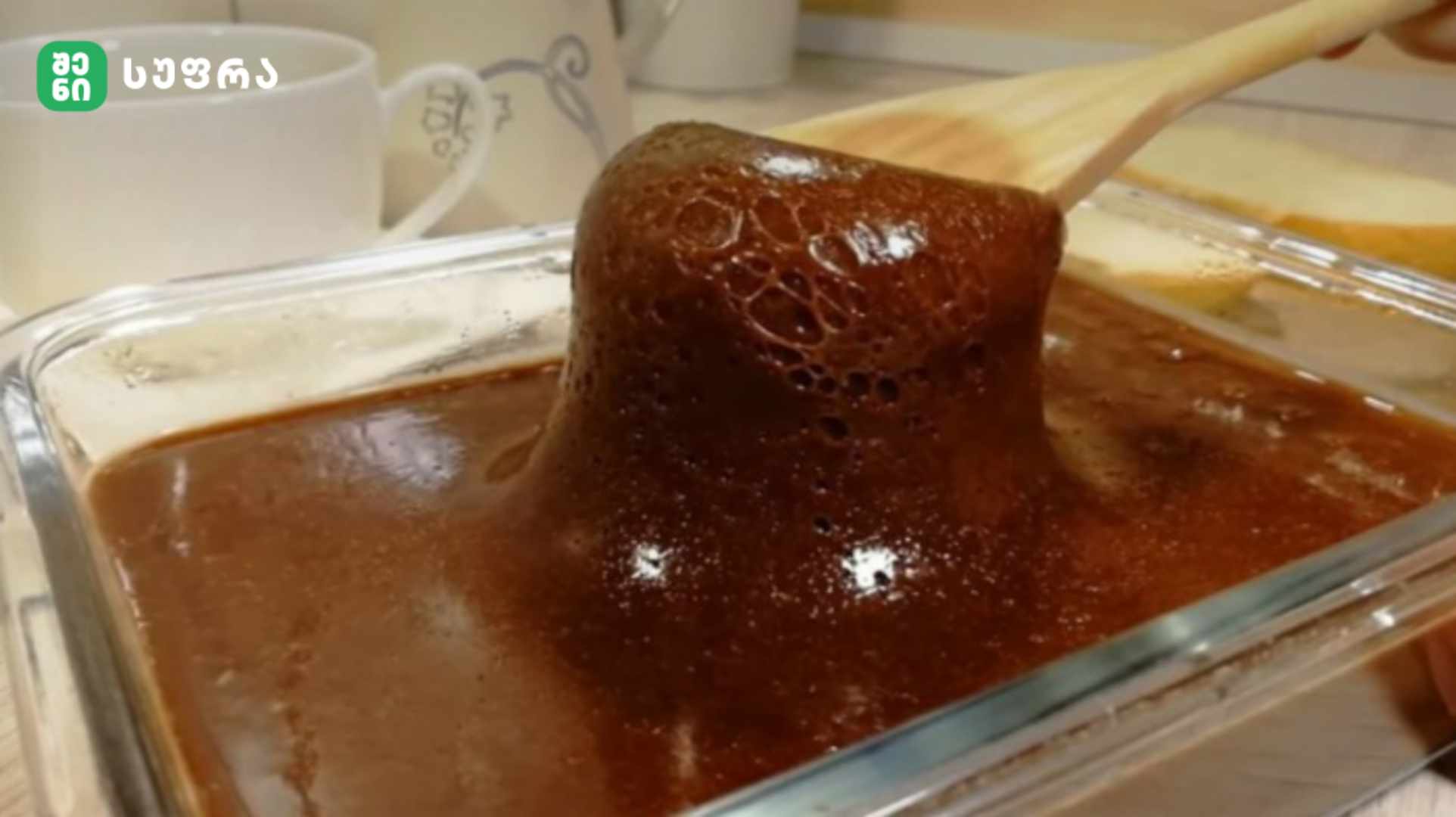 Chocolate lava cake being lifted with a wooden spatula from a glass baking dish.