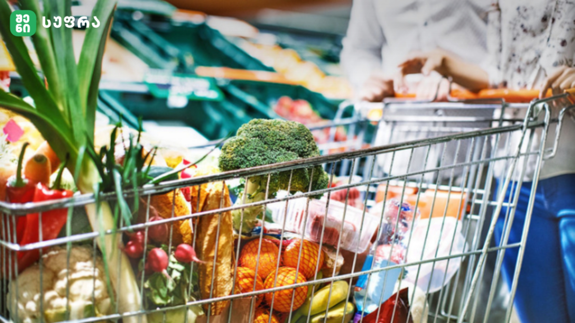 Shopping cart filled with fresh vegetables in a supermarket, with broccoli in the foreground.